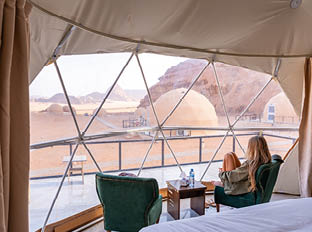 Tourist woman with long blonde hair in bubble tent at Wadi Rum protected area desert Jordan