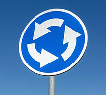 Roundabout crossroad road traffic sign against blue sky 