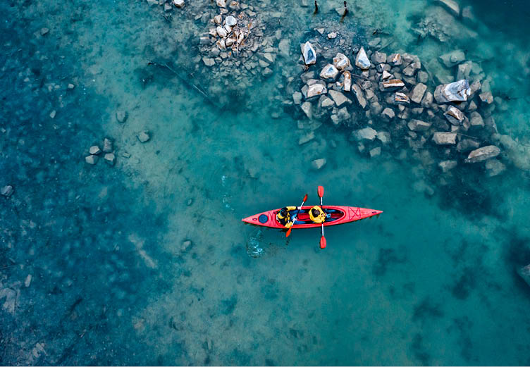 two athletic man floats on a red boat in calm blue waters river