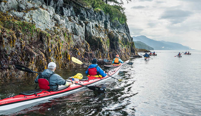 Canada, British Columbia. Sea kayakers paddle at low tide along the Vancouver Island shore on Johnstone Strait.