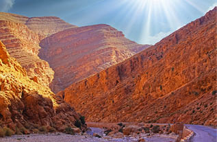 Beautiful red sandstone valley landscape, empty curved road, narrow canyon, morning sun rays - Todra (todgha) gorge, Morrocco