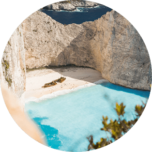 Famous shipwreck on Navagio beach with turquoise blue sea water surrounded by huge white cliffs. Famous landmark location on Zakynthos island, Greece. Farme shot between leaves.