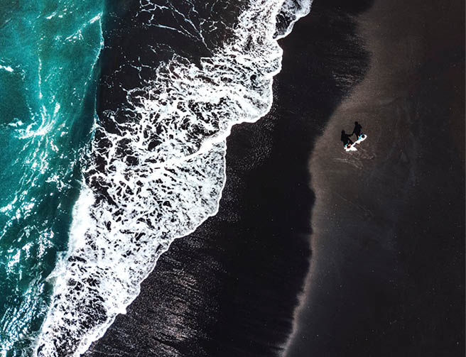 Happiness Couple enjoying on Black Sand Beach with white wave at Bali ,Indonesia
