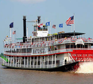 Raddampfer „Natchez“ mit rotem Schaufelrad und Flaggen f hrt auf einem Fluss