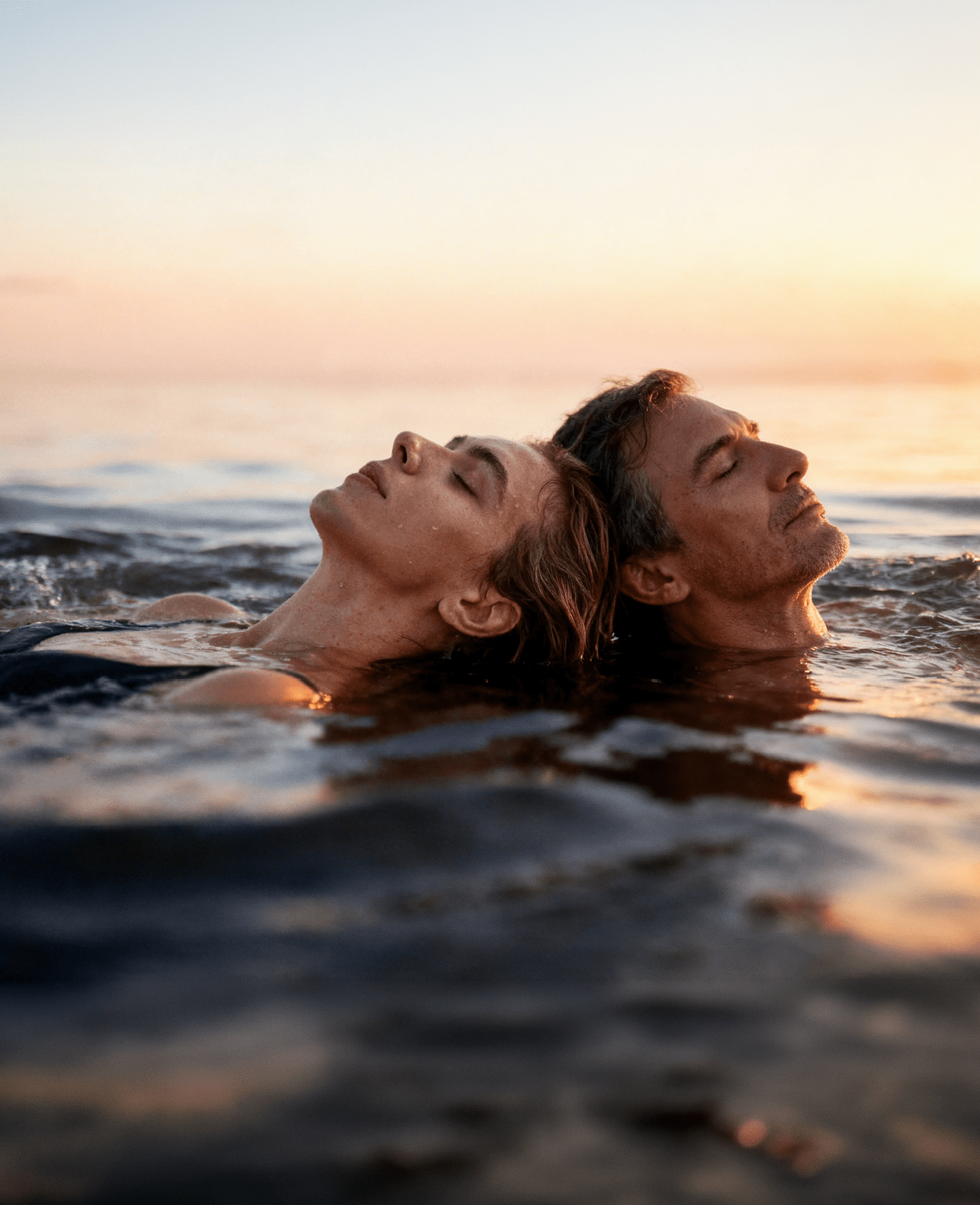 Paar treibt entspannt im Meer bei Sonnenuntergang