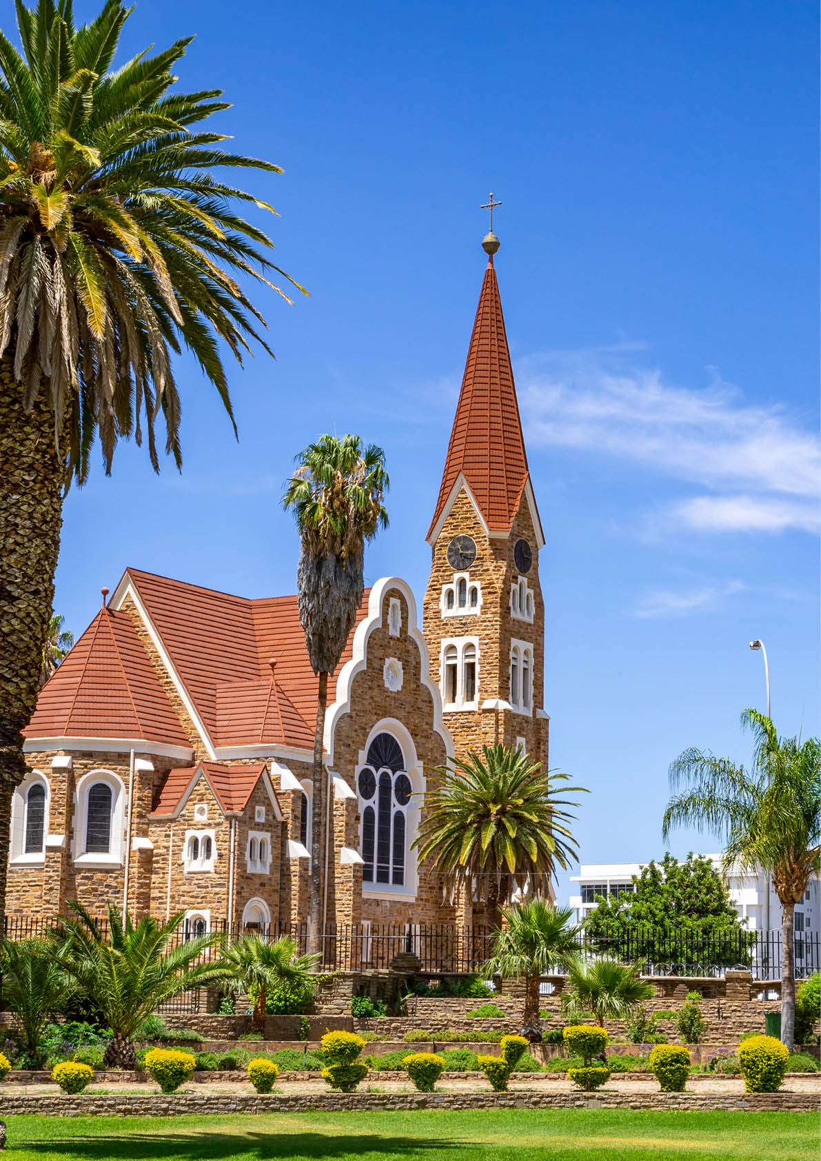 Kirche mit Turm zwischen Palmen und moderner Bebauung