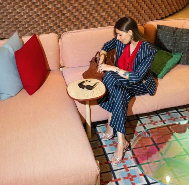 Frau sitzt auf modernem Sofa und sucht in Handtasche