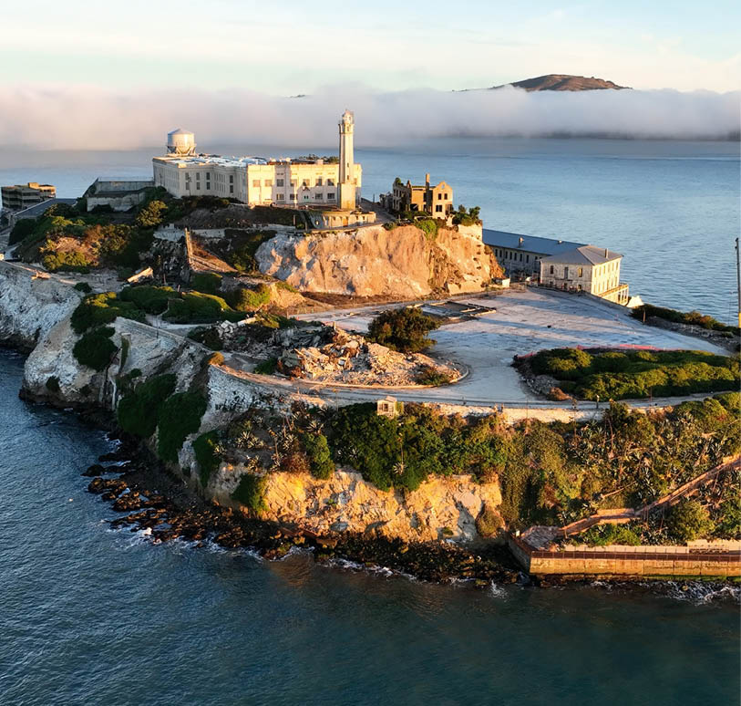 Insel mit Geb uden und Leuchtturm im Meer aus der Luft