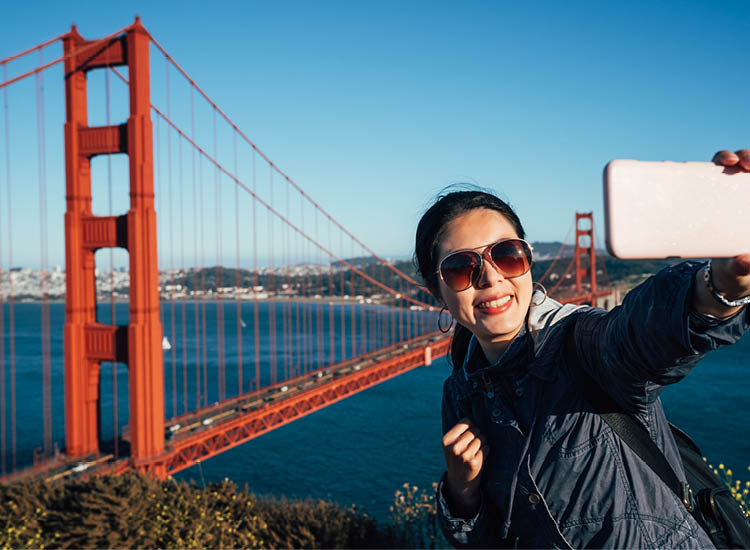 Frau macht Selfie vor Golden Gate Bridge ber dem Meer