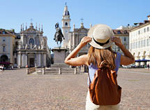 Holidays in Italy. Panoramic view of traveler girl walking in Piazza San Carlo square enjoying cityscape of Turin, Italy. Young female backpacker visiting Europe.