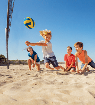 Portrait of happy teenage boy making bump pass during beach volleyball game with friends