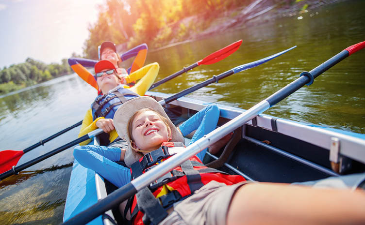 Happy kids kayaking on the river. Active boy with his sisters having fun and enjoying adventurous experience with kayak on a sunny day during summer vacation