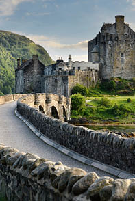 Evening light on restored Eilean Donan Castle on Island at three lochs with added stone arch footbridge Scottish Highlands Scotland UK