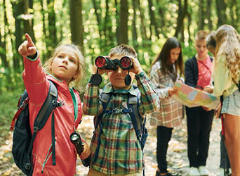 New places. Kids in green forest at summer daytime together.