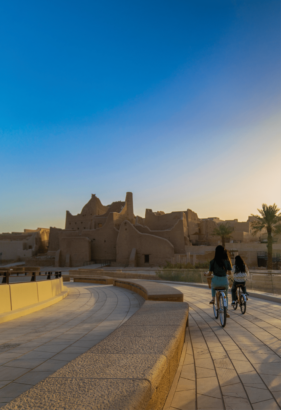 A family of three riding bicycles outside the Salwa Palace in the At-Turaif District