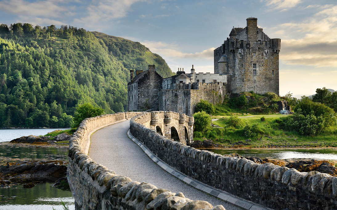 Evening light on restored Eilean Donan Castle on Island at three lochs with added stone arch footbridge Scottish Highlands Scotland UK