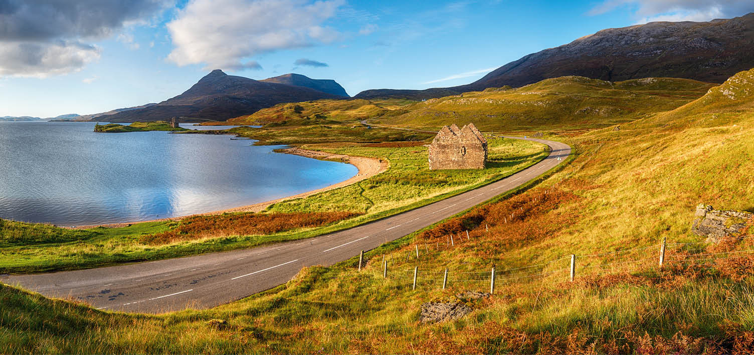 Autumn at Loch Assynt in Scotland with the ruins of Calda House and Ardvreck Castle in the far left, landmarks on the NC500 scenic driving route
