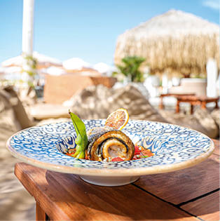 A vertical shot of a gourmet fish dish at a beachside restaurant