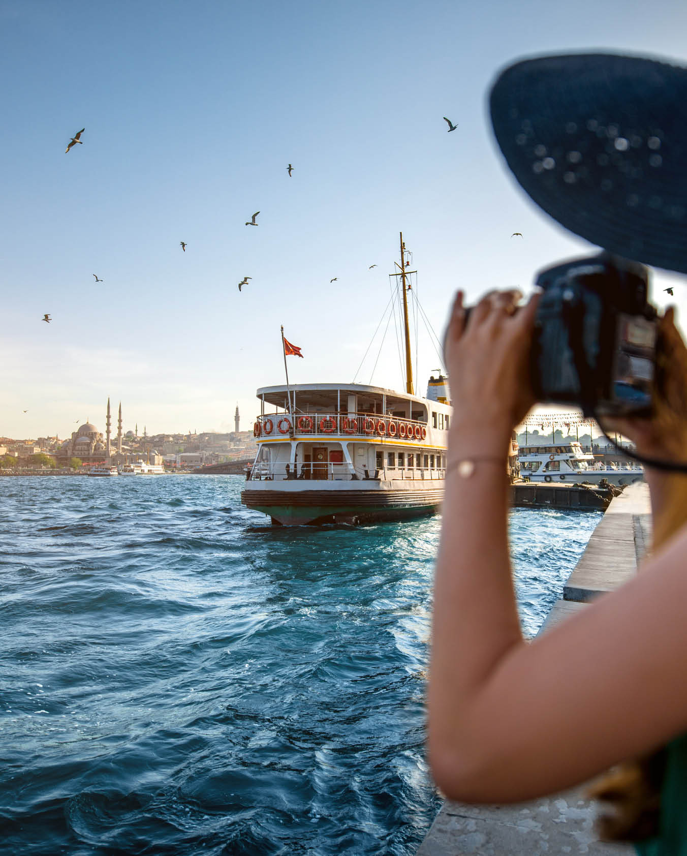 A woman taking a picture of a boat on the water. Beschreibung von KI generiert