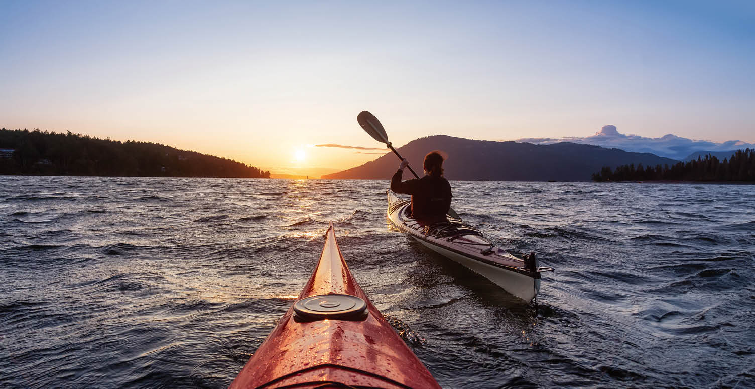 Adventurous Woman on Sea Kayak paddling in the Pacific Ocean. Sunny Summer Sunset. Taken near Victoria, Vancouver Islands, British Columbia, Canada. Concept: Sport, Adventure