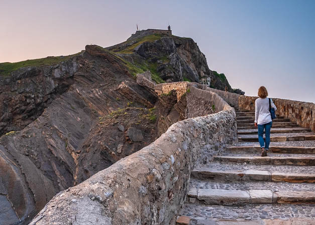 Ancient stone bridge leading to Gaztelugatxe islet at sunset Basque Country Spain symbol of journey solitude spirituality dramatic seascape inspiration