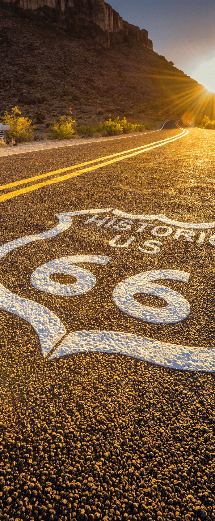 Street sign on historic route 66 in the Mojave desert photographed against the sun at sunset