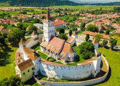 Aerial view of fortified church surrounded powerful thick walls in Transylvania overlooking the village in a beautiful summer day. Romania