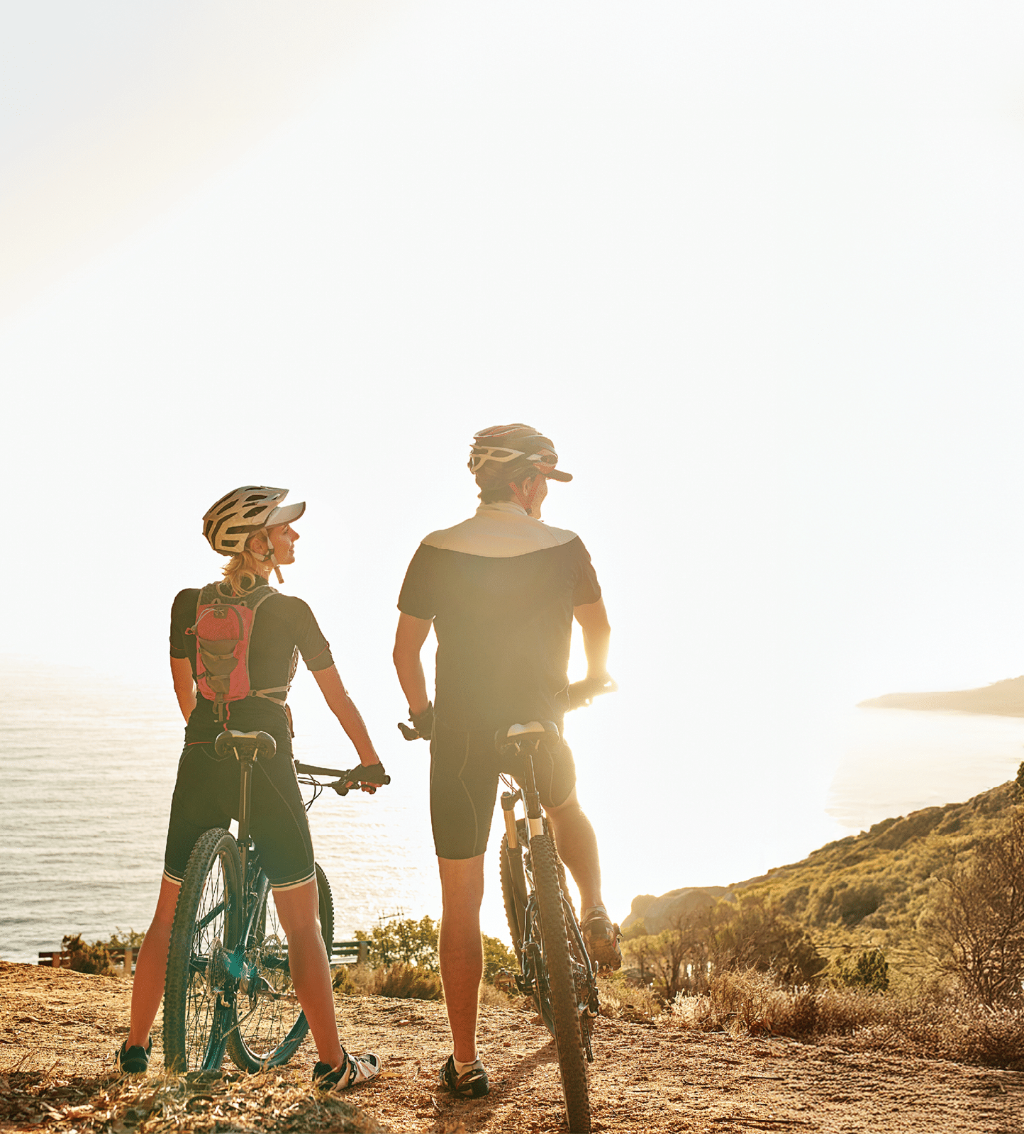 Mountain, bicycle and couple in nature for cycling, workout or training at sunset for marathon. Sports, fitness and team of athletes on bike for cardio exercise outdoor in dirt road for challenge