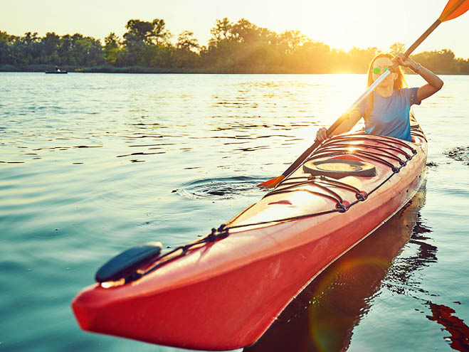Kayaking couple ride along the river at sunset