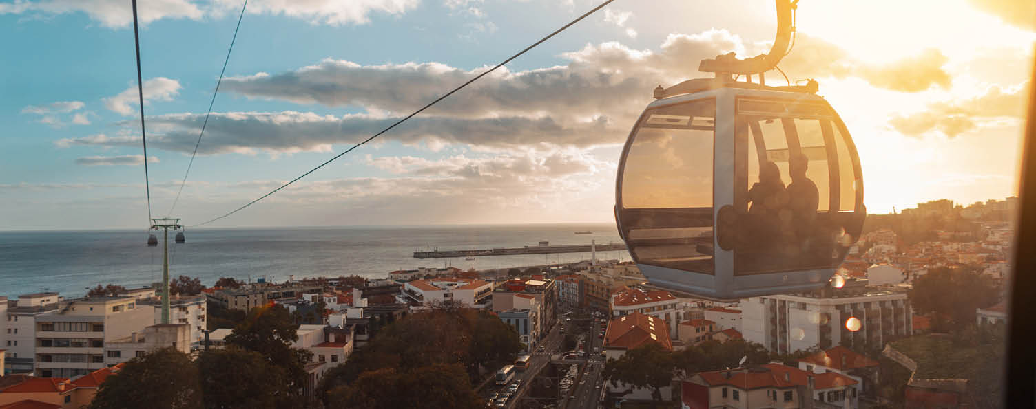 Beautiful city of Funchal with houses, funicular cable car, ocean and amazing sunset. Journey to Madeira Island. Travel