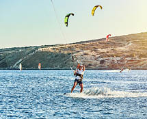 Strong sportsmen goes kitesurfing on tranquil azure sea water on Prasonisi beach at sunset on clear horizon in Greece in summer evening