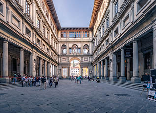 Piazzale degli Uffizi and famous art gallery in medieval palazzo with walking people, Florence, Italy