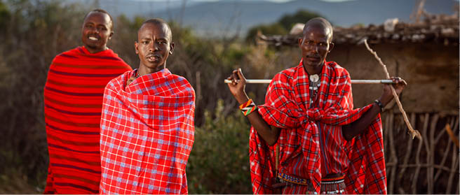 MASAI MARA, KENYA - Jan 01, 2013: A shallow focus shot of three African males with blankets wrapped around them