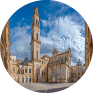 Weitl ufiger Platz mit barocker Kathedrale und hohem Glockenturm unter blauem Himmel.