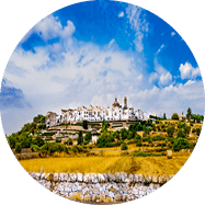 Historische Stadt mit Kirche auf H gelplateau, umgeben von terrassierter Agrarlandschaft.