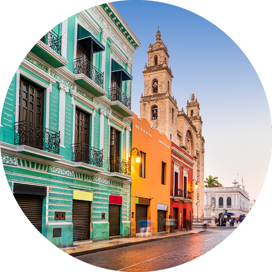 Yucatan: Farbige H userfronten in historischer Stra e mit Kathedrale unter klarem Himmel.