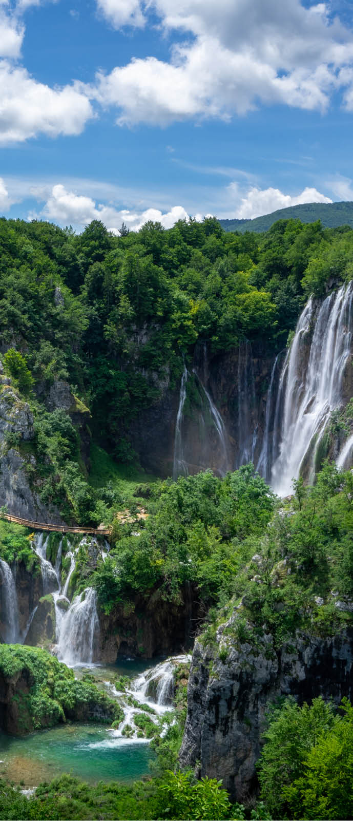 Mehrere Wasserf lle flie en ber Felsen in t rkisfarbene Seen, umgeben von dichter Vegetation.