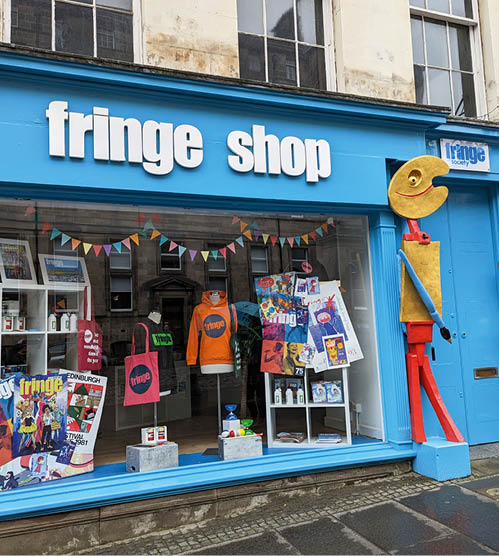 Blau gestrichener Laden mit Schriftzug „fringe shop“, Schaufensterdeko und bunten Figuren au en.