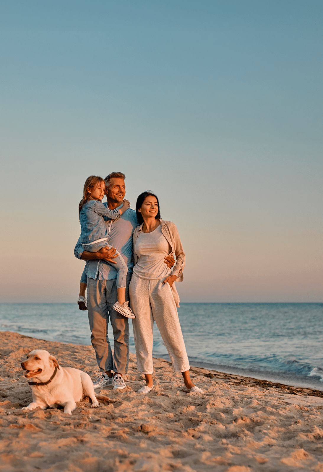 Familie mit Hund am Strand im Sonnenuntergang
