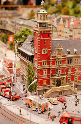 Modellstadt mit brennendem Geb ude und zahlreichen Feuerwehrfahrzeugen und Figuren im Einsatz.
