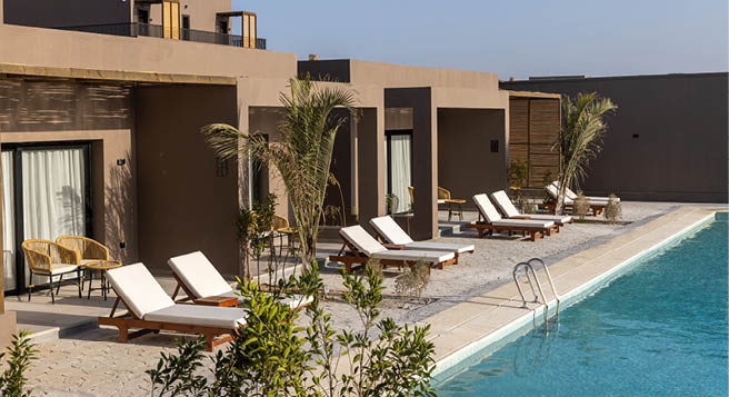 Liegest hle vor modernen Hotelzimmern mit direktem Zugang zu einem langen Au enpool.