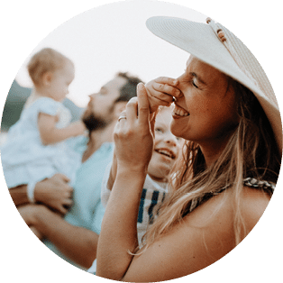 A young family with two toddler children standing on beach on summer holiday, having fun.