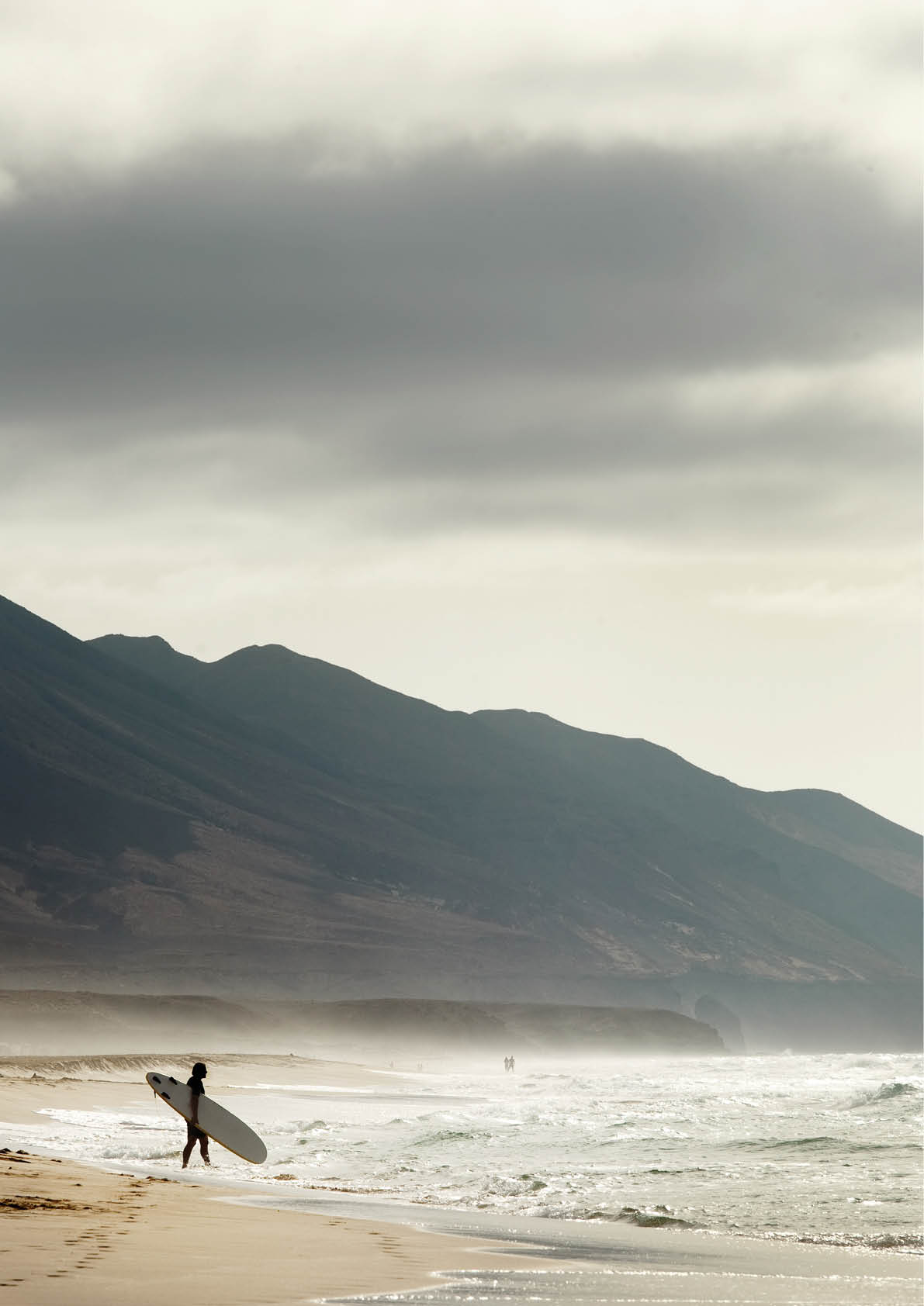 A vertical shot of a surfer on a Cofete beach, Fuerteventura, Canary Island