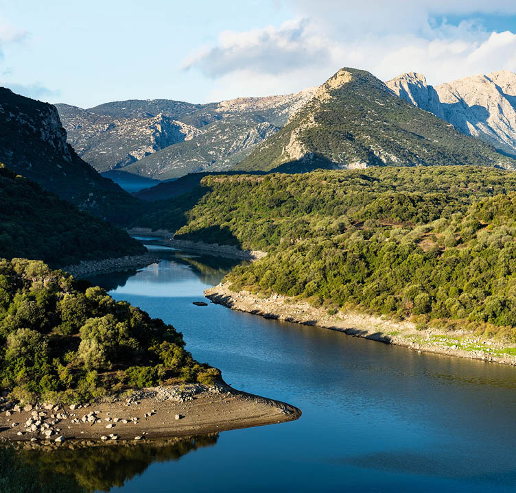 Stunning view of the Cedrino Lake (Lago del Cedrino) with the mountain range of Supramonte illuminated by a beautiful sunrise. Sardinia, Italy.