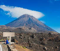 Pico do Fogo, volcano on the island of Fogo on Cabo Verde islands, with a woman sitting in the foreground.