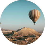 A long shot of multi-colored hot air balloons floating above the mountains