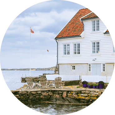 Traditional white wooden houses with red-tiled roofs by waterfront in beautiful fishing village, Farsund, Norway