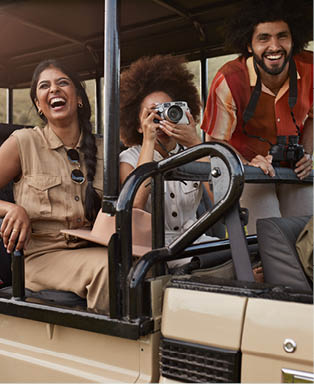 Young woman photographing while sitting with friends in safari vehicle at national wildlife park