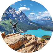 A hiker stands in awe on top of Bow Summit overlooking Peyto Lake in Banff National Park on the Icefields Parkway. The glacier-fed lake is famous for its bright turquoise colored waters in the summer.