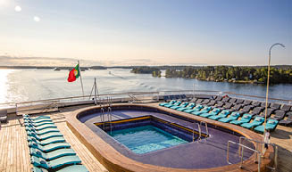 Oasis Pool with lounge chairs on Navigator Deck of cruise ship Vasco da Gama (nicko cruises) during passage of Stockholm Archipelago, near Stockholm, Sweden